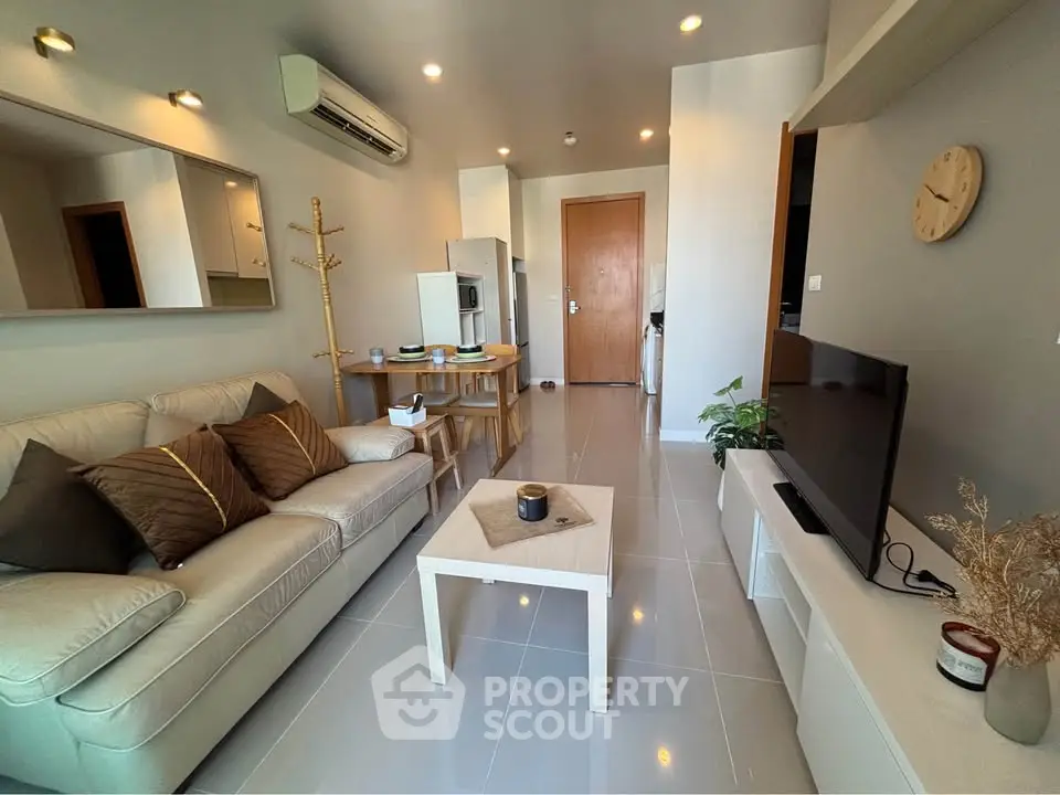 Modern living room with sleek furniture and neutral tones, featuring a cozy sofa and stylish decor.