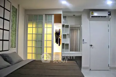 Modern bedroom with sliding closet doors and air conditioning unit, featuring stylish decor and ample storage space.