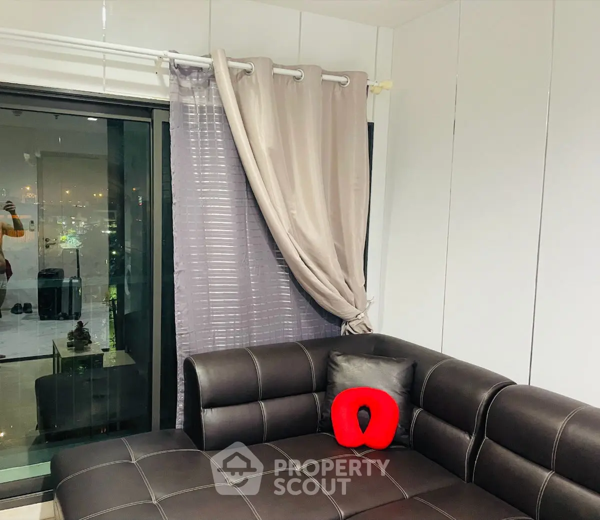 Modern living room with leather sofa and city view through large window.
