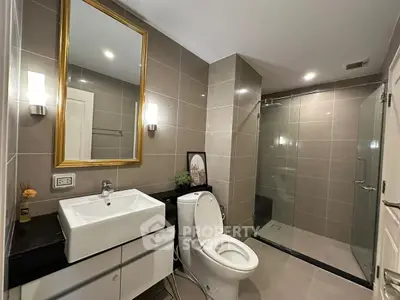 Modern bathroom with sleek design, featuring a glass shower and elegant fixtures.