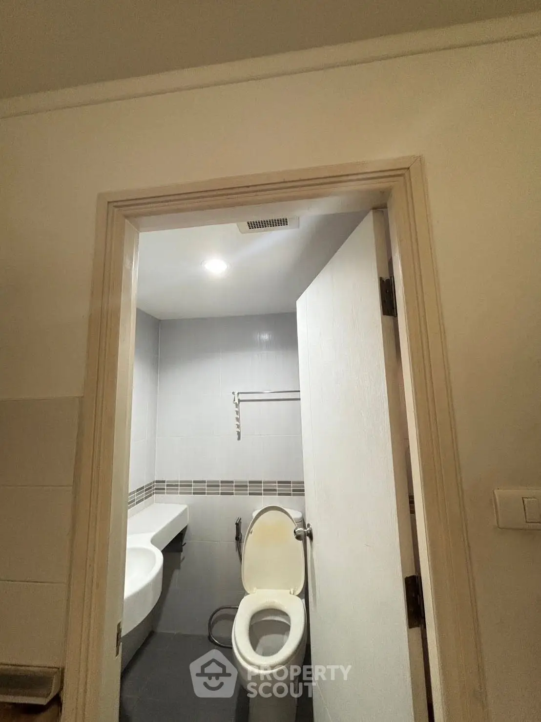 Modern bathroom with sleek design and neutral tones, featuring a toilet and built-in sink.