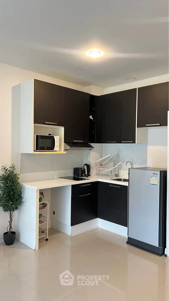Modern kitchen with sleek black cabinets and compact fridge in stylish apartment