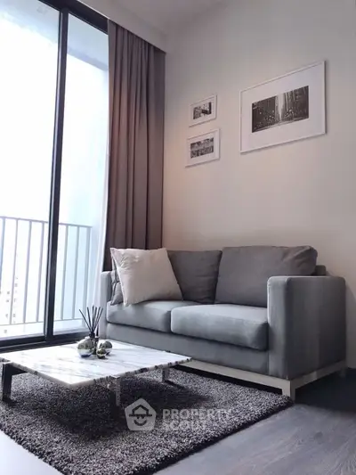 Modern living room with gray sofa, stylish coffee table, and balcony view.