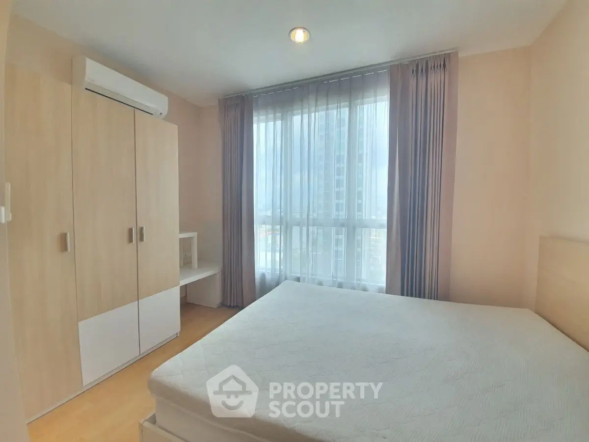Bright and cozy bedroom with large window and modern furnishings, perfect for relaxation.