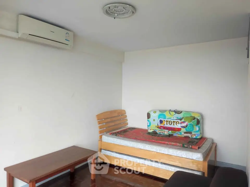 Cozy bedroom with single bed, air conditioning, and wooden furniture, perfect for a minimalist lifestyle.