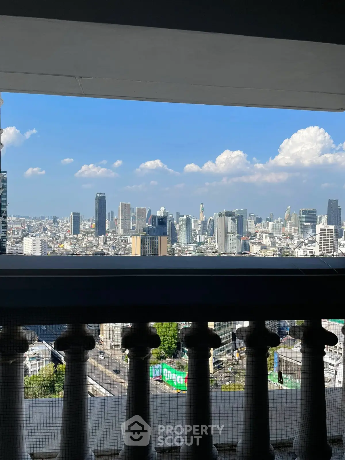 Stunning cityscape view from a high-rise balcony with clear blue skies.