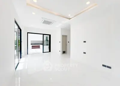 Spacious modern living room with sleek white interior and large windows.