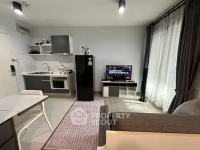 Modern open-layout living room with kitchen, featuring sleek furniture and natural light.