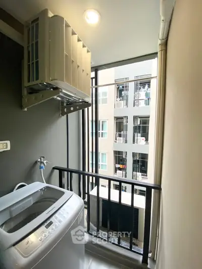Compact balcony with washing machine and city view, ideal for urban living convenience.
