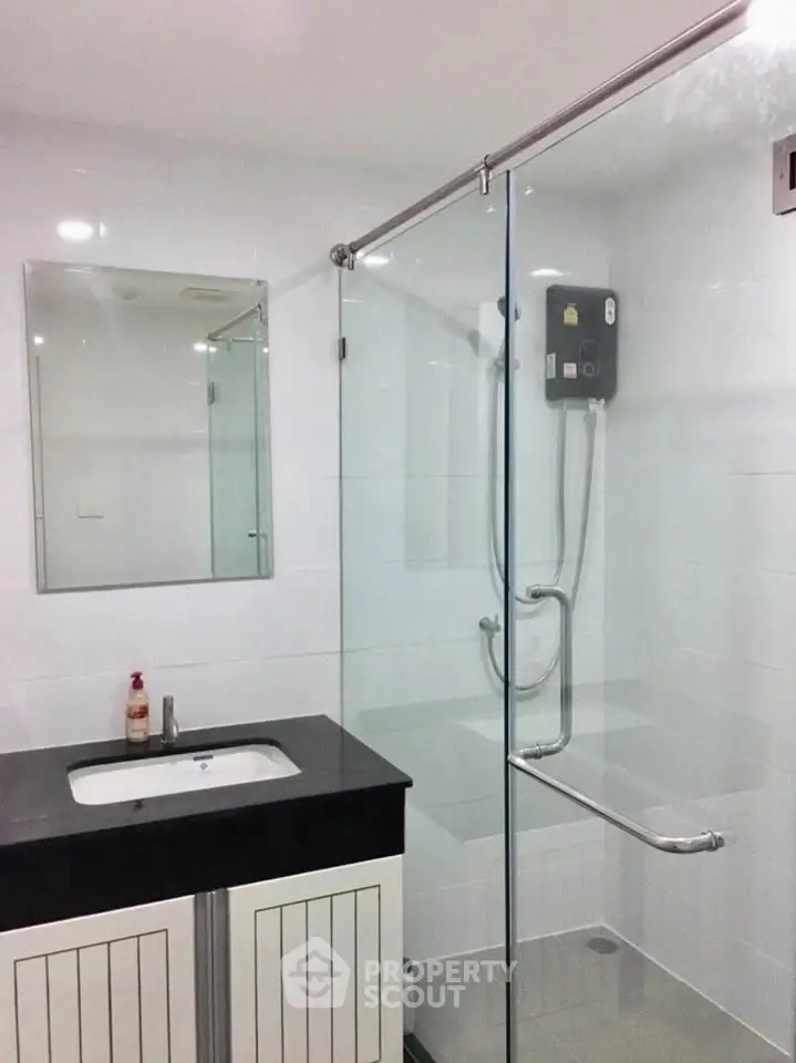 Modern bathroom with glass shower enclosure and sleek vanity in a contemporary home.