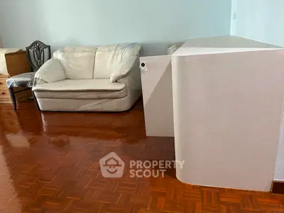 Spacious living room with polished wooden floors and cozy furniture, perfect for relaxation.