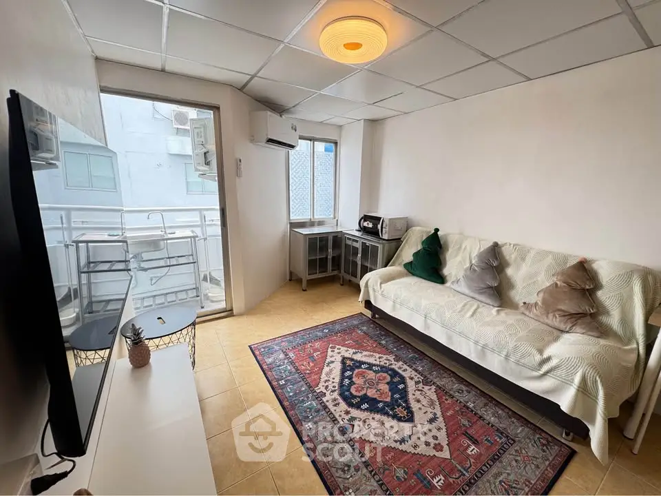 Cozy living room with balcony access, featuring a modern TV setup and stylish decor.