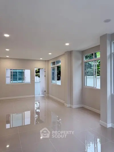 Spacious and bright living room with large windows and glossy tiled floors in modern home.
