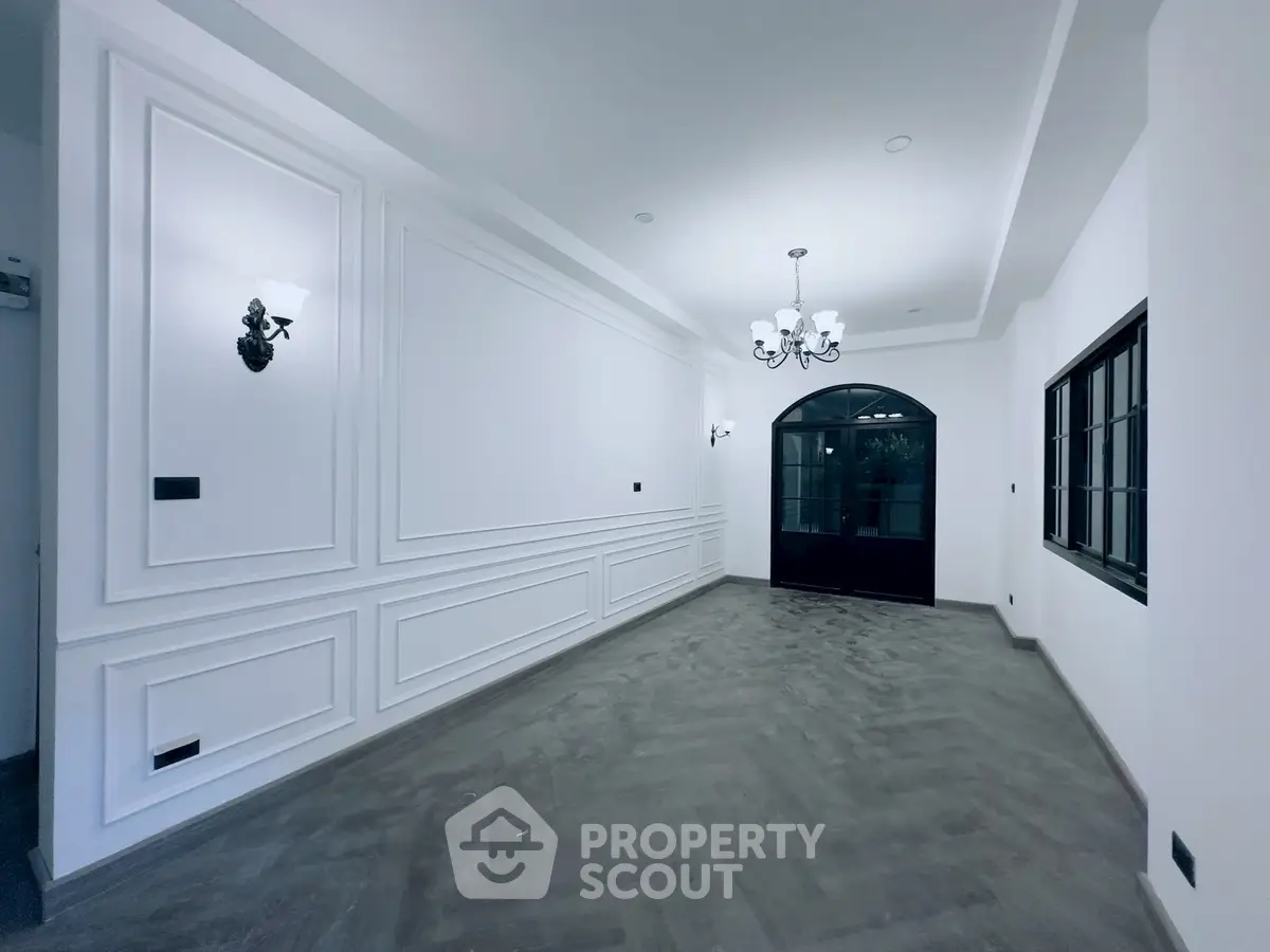 Elegant empty living room with classic wall paneling and chandelier lighting
