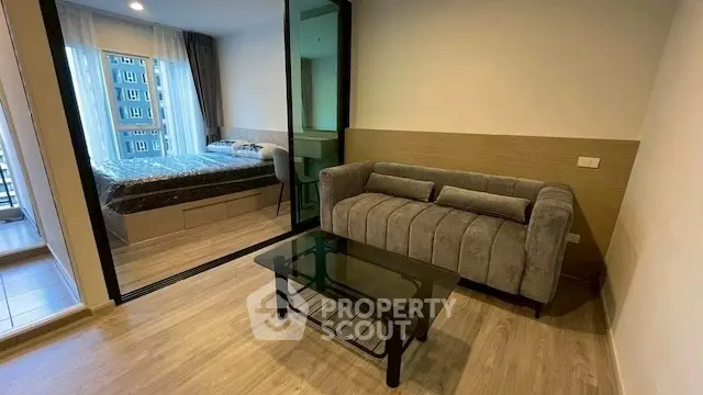 Modern studio apartment with glass partition, cozy living area, and stylish bedroom.