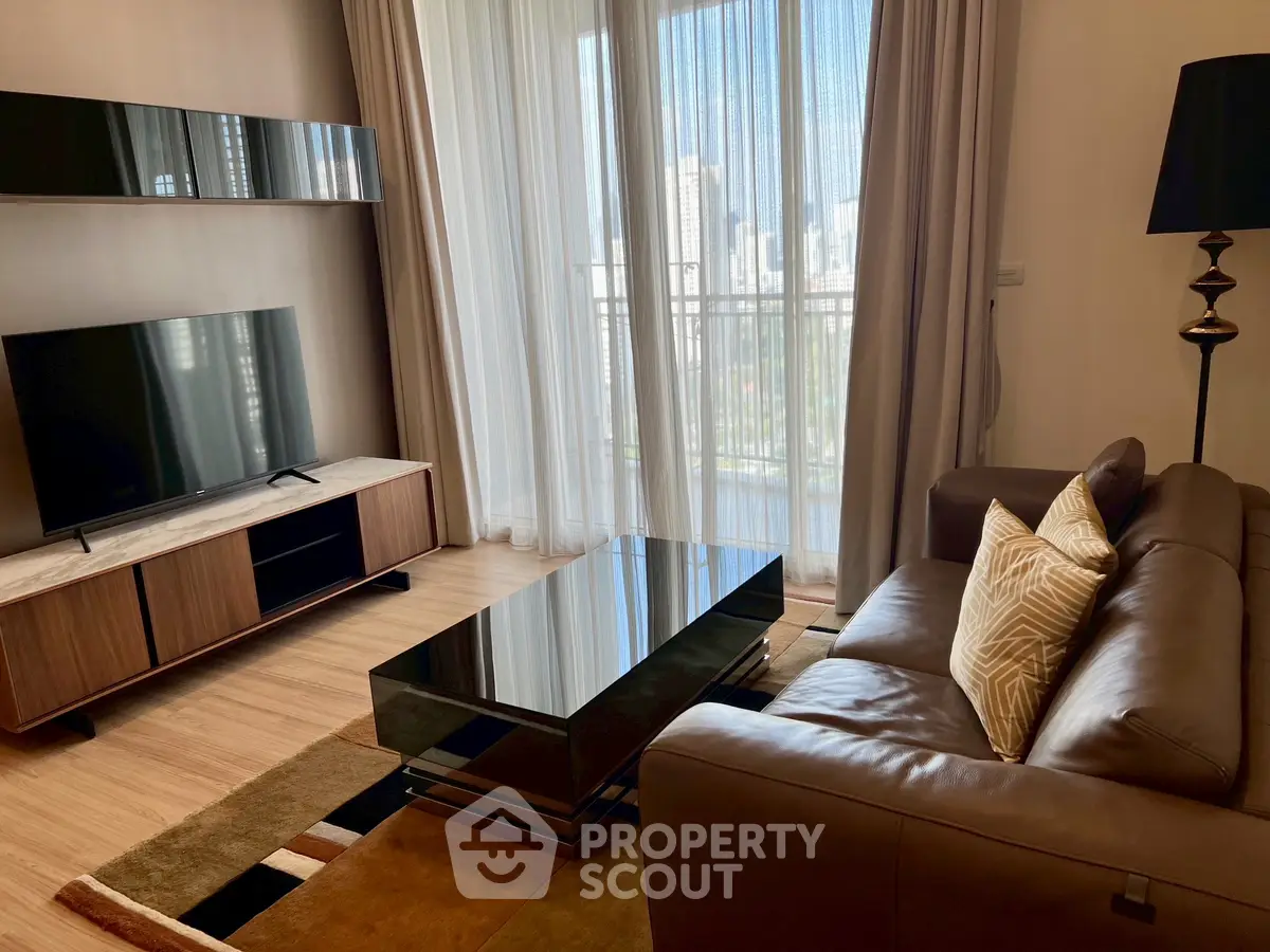 Modern living room with leather sofa, sleek TV unit, and large window with city view.