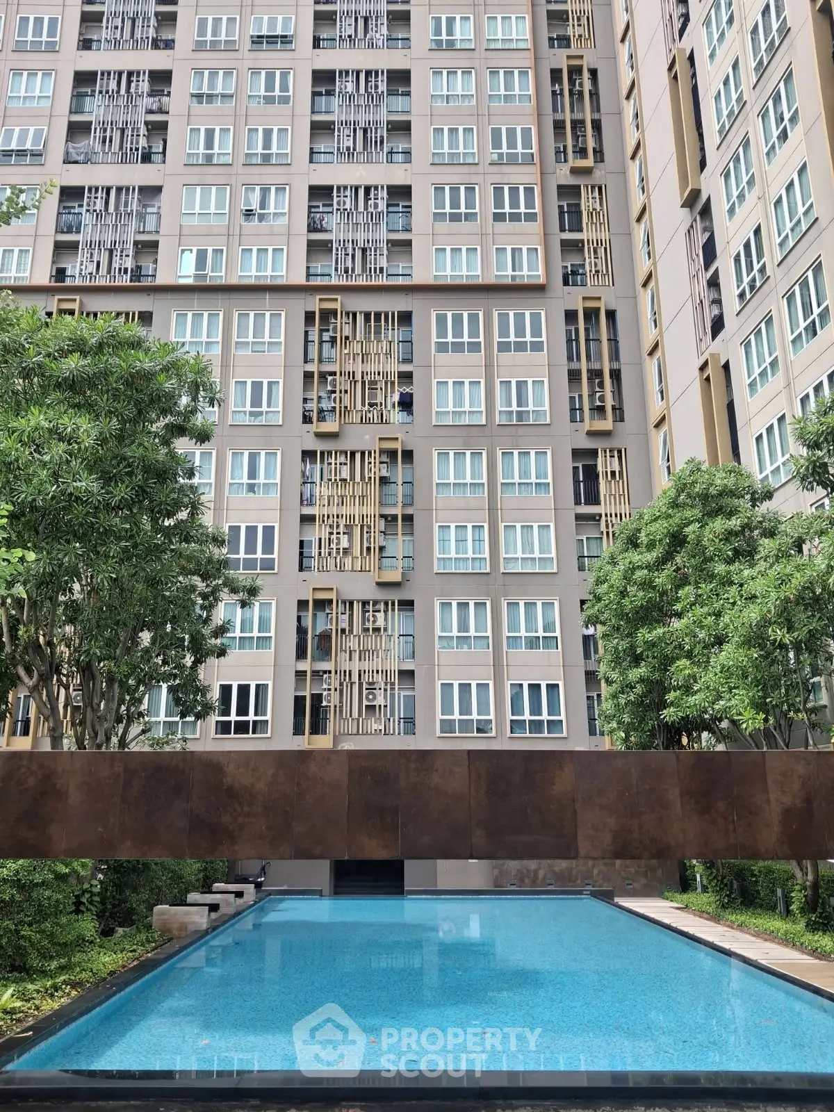 Modern high-rise building with a serene outdoor pool and lush greenery, perfect for urban living.