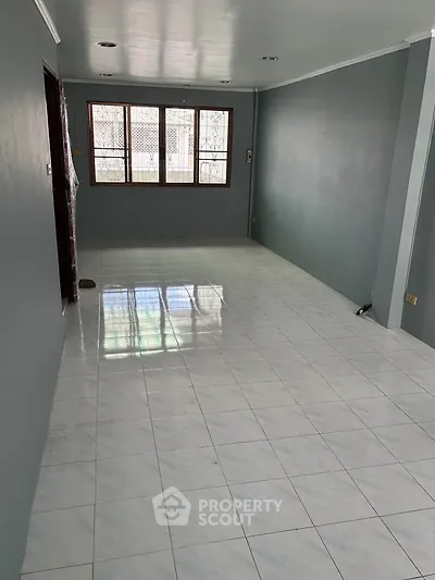 Spacious empty living room with tiled flooring and large windows for natural light.