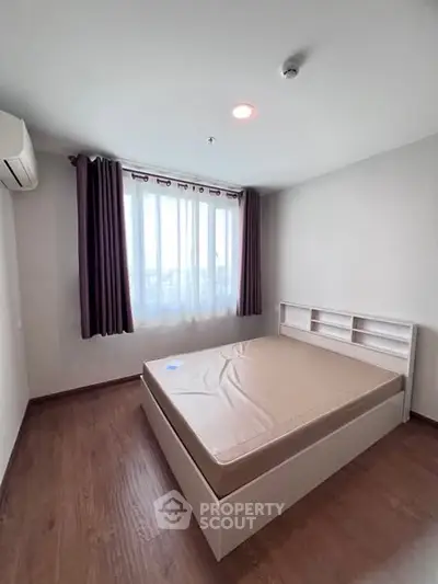 Spacious bedroom with large window and modern furnishings in a bright apartment.