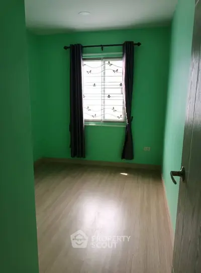 Bright green bedroom with wooden flooring and window curtains