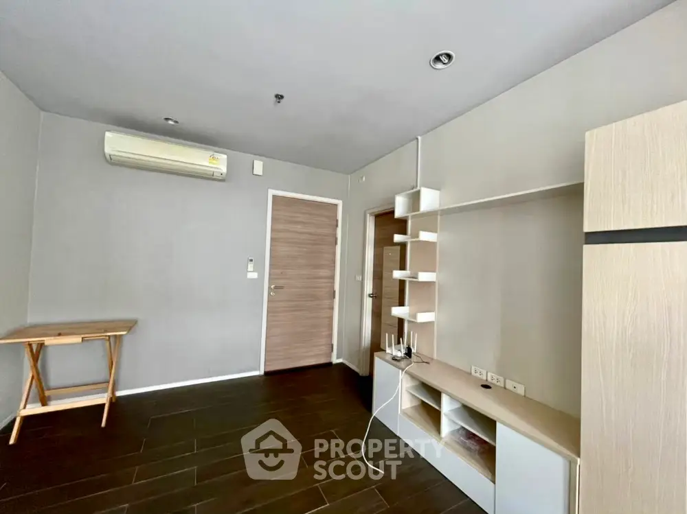 Modern unfurnished living room with sleek wooden flooring and built-in shelving