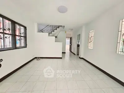 Spacious open-plan living area with staircase and large windows