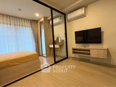 Modern bedroom with glass partition, TV, and stylish decor in a contemporary apartment.