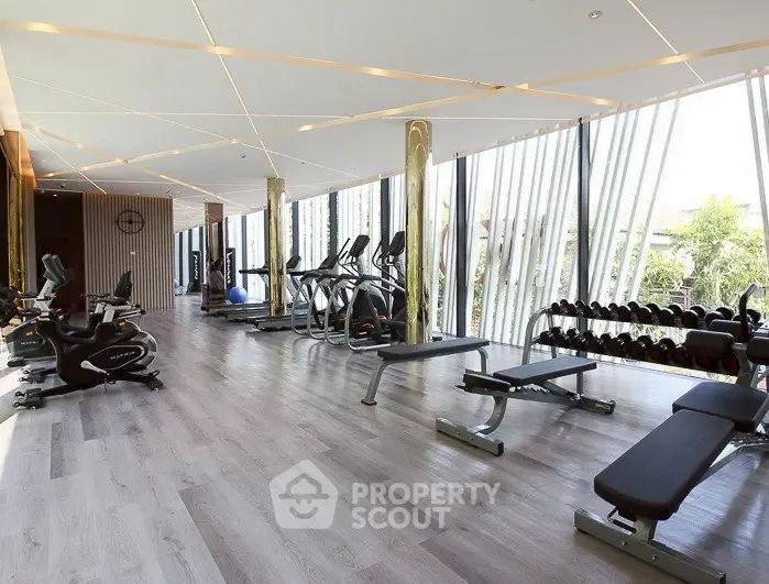 Spacious modern gym with state-of-the-art equipment and floor-to-ceiling windows.