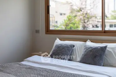 Cozy bedroom with large window and stylish bedding in modern apartment