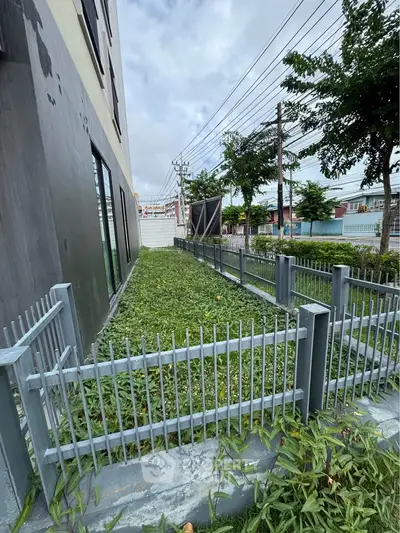 Modern building exterior with landscaped garden and secure fencing, ideal for urban living.
