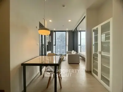 Modern open-plan living and dining area with city view, featuring sleek furniture and large windows.