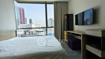 Modern bedroom with city view, featuring sleek furniture and large windows for natural light.