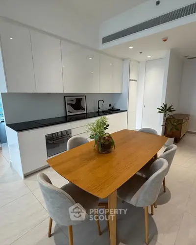 Modern kitchen with sleek cabinetry and dining area in contemporary apartment
