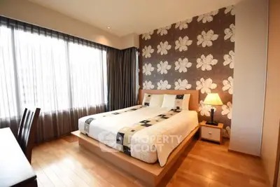 Spacious bedroom with floral accent wall and natural light