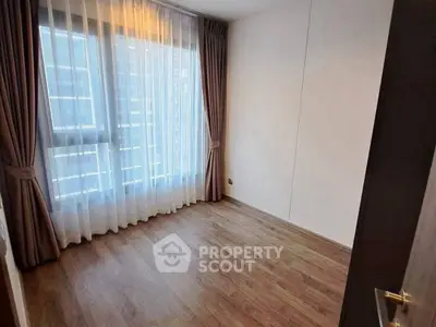 Spacious empty room with large window and wooden flooring, perfect for customization.