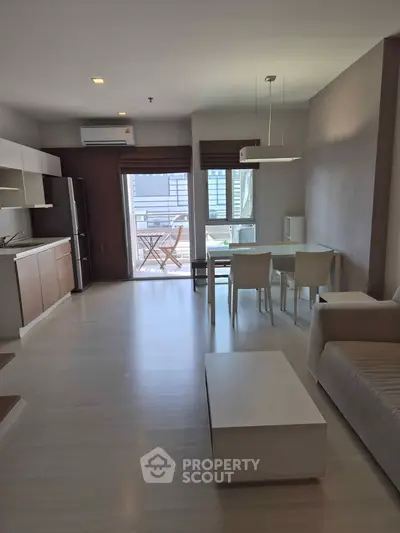 Modern open-plan living room with dining area and balcony access in a stylish apartment.