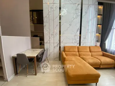 Modern living room with stylish marble wall and cozy orange sofa in a contemporary apartment.
