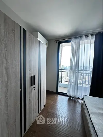 Modern bedroom with wooden flooring and balcony view in high-rise apartment