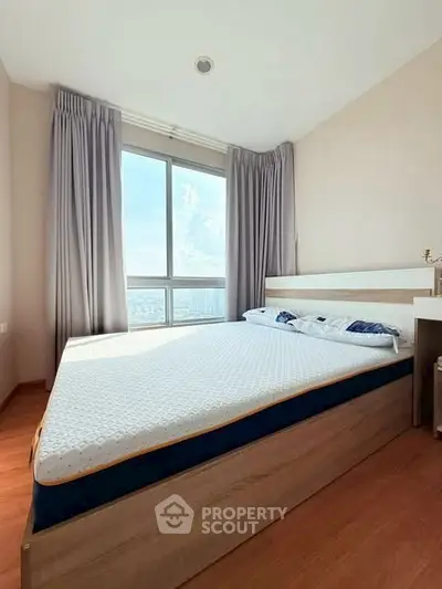 Bright bedroom with large window and modern bed frame, offering city views.