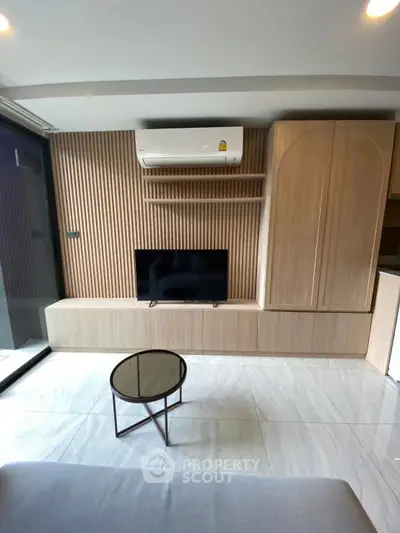 Modern living room with sleek wooden paneling, wall-mounted TV, and stylish air conditioning unit.