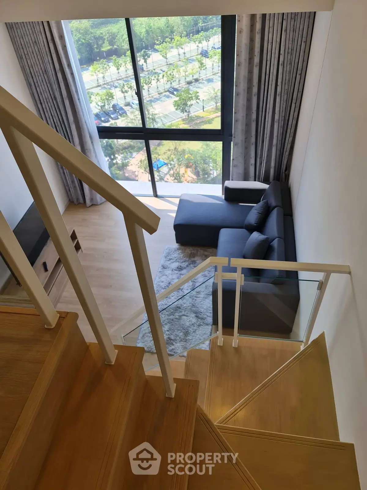 Modern duplex living room with large windows and stylish furniture, offering a stunning view.