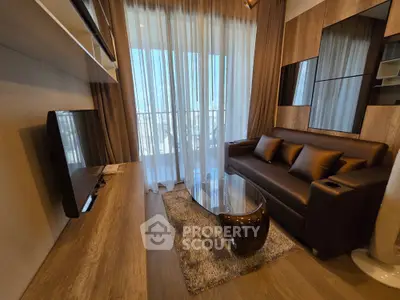 Modern living room with stylish decor and balcony view, featuring a sleek sofa and entertainment setup.