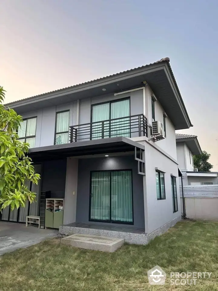 Modern two-story house with balcony and lawn, ideal for family living.