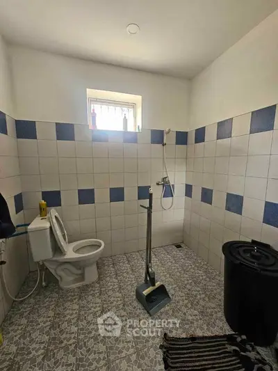 Spacious bathroom with tiled walls and floor, featuring a shower and toilet, ideal for modern living.