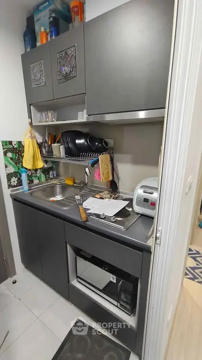 Compact kitchen with modern appliances and sleek cabinetry in a cozy apartment setting.