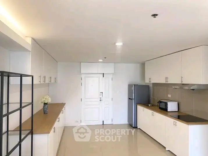Spacious modern kitchen with sleek cabinetry and stainless steel appliances in a bright apartment.