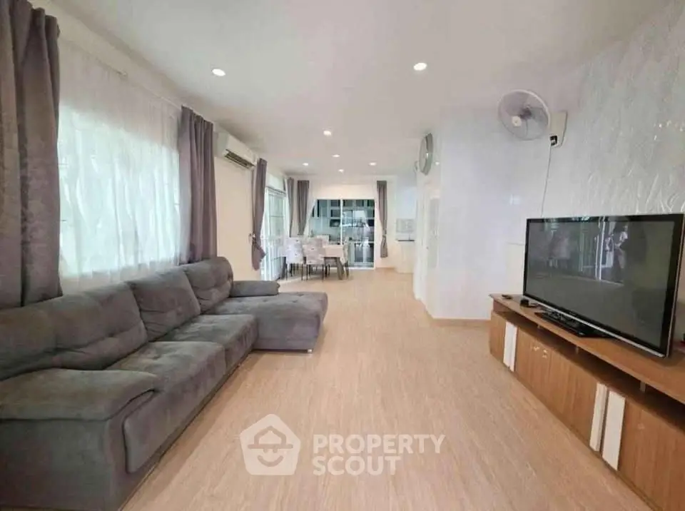 Spacious living room with modern decor and large TV, perfect for family gatherings.