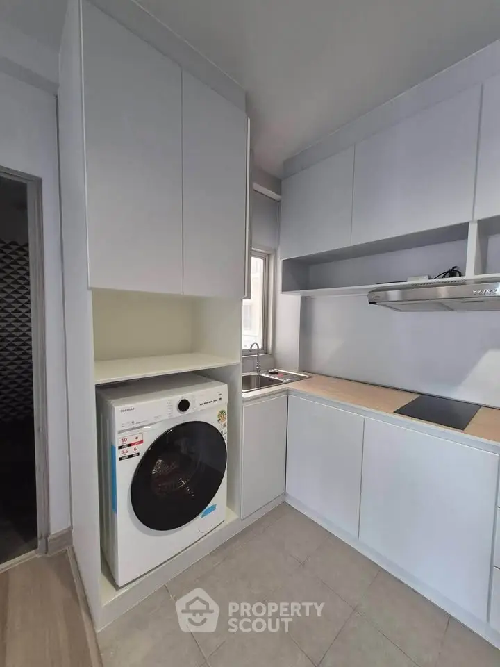 Modern kitchen with sleek cabinetry and built-in washing machine, featuring a minimalist design and efficient layout.