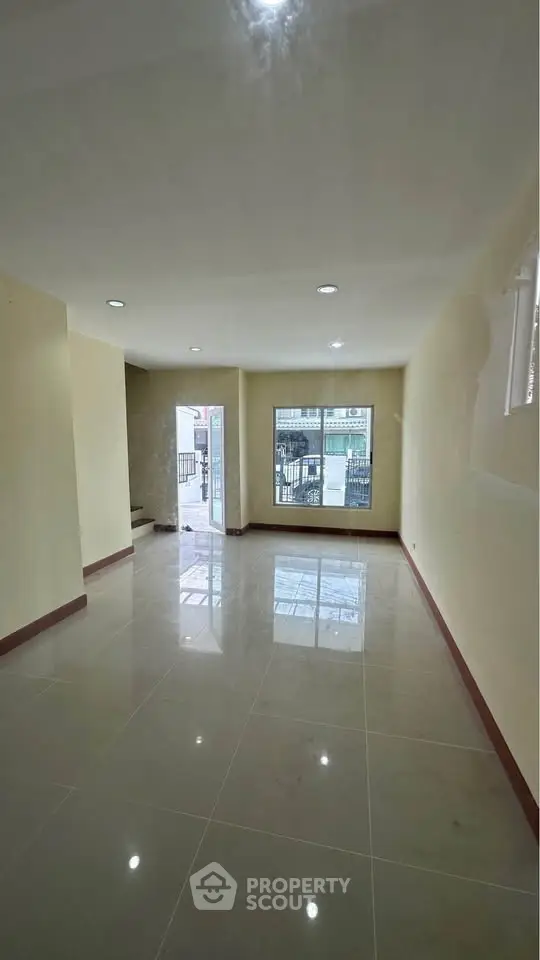 Spacious unfurnished living room with large windows and glossy tiled floors.