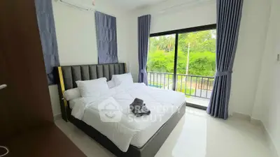 Bright bedroom with large window and lush green view, featuring modern decor and cozy bedding.
